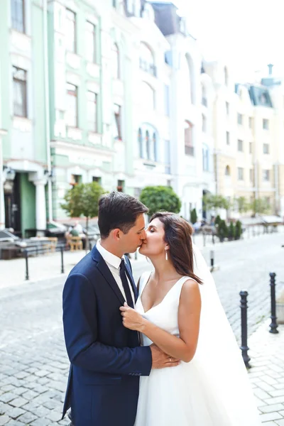 华丽的婚礼夫妇走在城市里 这对新婚夫妇穿着时髦的西服 穿着漂亮的白色礼服 在城市的街道上散步 在一起 结婚的概念 — 图库照片