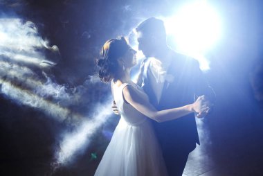 Yeni evlilerin ilk düğün dansı. Karanlıkta dans eden düğün çifti. Damat bir restoranın ortasında gelinin elini tutuyor ve onunla dans ediyor. Mutlu gelin ve damat ve ilk dansları. 