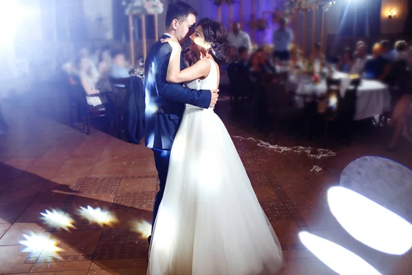 First wedding dance of newlywed. Groom holds bride\'s hand dancing with her in the middle of a restaurant. Touching and emotional first dance of the couple on their wedding with lights.