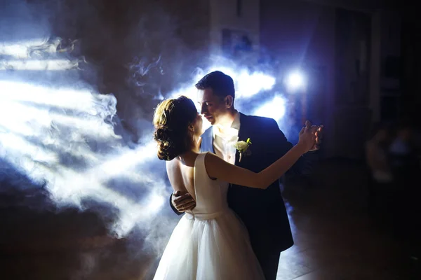 First wedding dance of newlywed. Wedding couple dancing in the darkness. Groom holds bride\'s hand dancing with her in the middle of a restaurant. Happy bride and groom and their first dance.