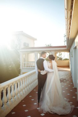 Günbatımında poz veren mutlu bir çift. Damat geline sarılır ve onu öper. Gün batımında seksi öpüşen şık aşıklar. Aşıklar birbirini sever. Birlikte. Düğün için. Evlilik..