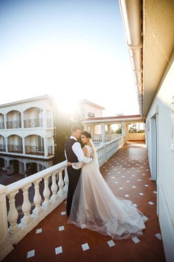 Günbatımında poz veren mutlu bir çift. Damat geline sarılır ve onu öper. Gün batımında seksi öpüşen şık aşıklar. Aşıklar birbirini sever. Birlikte. Düğün için. Evlilik..