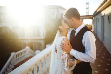 Günbatımında poz veren mutlu bir çift. Damat geline sarılır ve onu öper. Gün batımında seksi öpüşen şık aşıklar. Aşıklar birbirini sever. Birlikte. Düğün için. Evlilik..