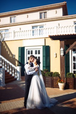 Yeni evliler şefkatle sarılır, öpüşür ve birbirlerinden hoşlanırlar. Aşıkların yürüyüşü. İnanılmaz gülümseyen bir düğün çifti. Güzel gelin ve şık damat. Romantik bir an. Sevgi. Birlikte. Düğün için. Evlilik..