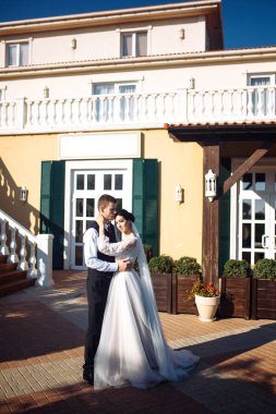 Yeni evliler şefkatle sarılır, öpüşür ve birbirlerinden hoşlanırlar. Aşıkların yürüyüşü. İnanılmaz gülümseyen bir düğün çifti. Güzel gelin ve şık damat. Romantik bir an. Sevgi. Birlikte. Düğün için. Evlilik..