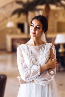 Uzun bir duvağı olan, moda gelinlikli güzel bir gelin. Çekici genç gelin inanılmaz derecede mutlu. Düğün saç stili, makyajı ve zarif beyaz gelinliğiyle muhteşem bir gelin..