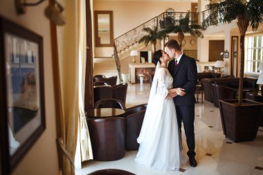Genç bir çift romantik anların tadını çıkarıyor. Harika bir çiftin çok güzel bir düğünü. Siyah takım elbiseli şık bir damat beyaz elbiseli güzel bir gelini nazikçe kucaklıyor. Birlikte. Aşk.