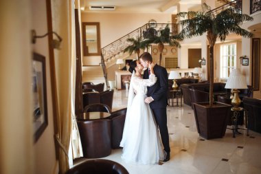 Genç bir çift romantik anların tadını çıkarıyor. Harika bir çiftin çok güzel bir düğünü. Siyah takım elbiseli şık bir damat beyaz elbiseli güzel bir gelini nazikçe kucaklıyor. Birlikte. Aşk.