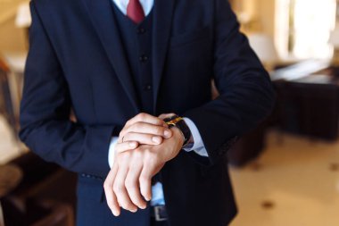 Şık erkek kol saati, adam saate bakıyor. İş adamı saati, iş adamı kol saatini kontrol ediyor. Kol saatini ayarlayan siyah takım elbiseli damadın elleri. 