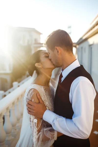 一对时髦的新婚夫妇在日落时摆姿势 新郎拥抱并亲吻新娘 夕阳西下时 性感的亲吻成为一对恋人的时尚 情侣们互相享乐 在一起 — 图库照片