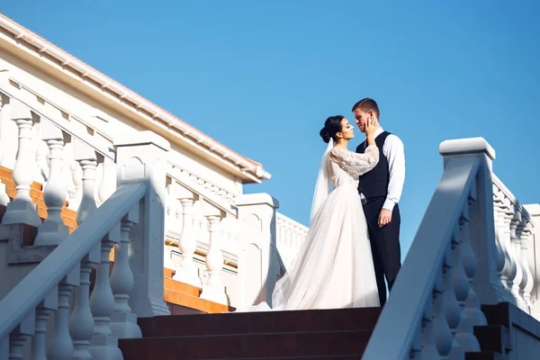 新娘和新郎在楼梯的台阶上 优雅时尚的年轻夫妇拥抱在一起 在楼梯上享受彼此 新婚夫妇在户外的楼梯上摆姿势谈恋爱 在一起 — 图库照片