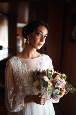 Düğün buketi olan güzel bir gelin. Profesyonel makyajlı ve saç stili olan güzel bir kadın. Şık, mutlu gelin sabah hazırlanıyor. Düğün günü. Moda Gelini.