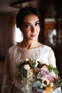 Düğün buketi olan güzel bir gelin. Profesyonel makyajlı ve saç stili olan güzel bir kadın. Şık, mutlu gelin sabah hazırlanıyor. Düğün günü. Moda Gelini.