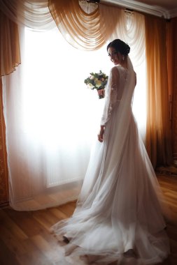 Düğün buketi olan güzel bir gelin. Profesyonel makyajlı ve saç stili olan güzel bir kadın. Şık, mutlu gelin sabah hazırlanıyor. Düğün günü. Moda Gelini.