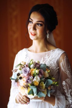 Düğün buketi olan güzel bir gelin. Profesyonel makyajlı ve saç stili olan güzel bir kadın. Şık, mutlu gelin sabah hazırlanıyor. Düğün günü. Moda Gelini.