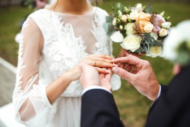 Nişan yüzükleri. Evli çiftler nikah töreninde alyanslarını takarlar. Damat, sevgili karısının parmağına yüzük taktı. Düğün detaylarını düşün. Mutlu bir aile. Birlikte.