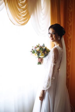 Düğün buketi olan güzel bir gelin. Profesyonel makyajlı ve saç stili olan güzel bir kadın. Şık, mutlu gelin sabah hazırlanıyor. Düğün günü. Moda Gelini.