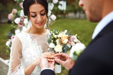 Nişan yüzükleri. Evli çiftler nikah töreninde alyanslarını takarlar. Damat, sevgili karısının parmağına yüzük taktı. Düğün detaylarını düşün. Mutlu bir aile. Birlikte.