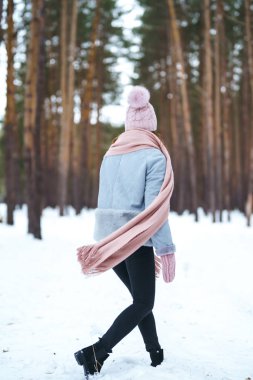 Genç ve güzel bir kadın ormanda gülüyor ve eğleniyor. Kız mavi bir ceket, örgü bir şapka, atkı ve eldiven giyiyor. Ormanda mutlu kış zamanları. Kutlama kavramı, Noel.