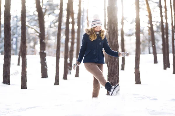 Happy young woman plays with a snow in sunny winter day. Girl enjoys winter, frosty day.  Playing with snow on winter holidays, a woman throws white, loose snow into the air. Walk in winter forest.