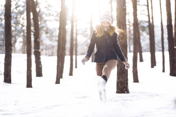 Happy young woman plays with a snow in sunny winter day. Girl enjoys winter, frosty day.  Playing with snow on winter holidays, a woman throws white, loose snow into the air. Walk in winter forest.