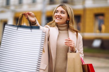 Güzel bir kız çok renkli çantalarla alışveriş yapıyor. Şehir caddesinde alışveriş torbaları tutan genç bir kadın. Tüketim, alışveriş, satış, yaşam tarzı konsepti. Kara Cuma.