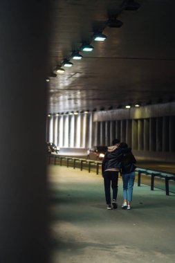 Karanlık bir tünelde el ele tutuşan genç çiftin arka görüntüsü. Tarz sahibi aşık çift siyah arka planda birbirlerine ışıklarla sarılıyorlar. Birlikte. Aşk, romantik, şefkat konsepti.