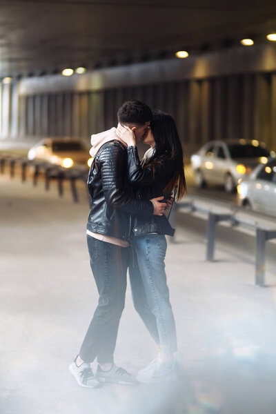 Young couple in love hug each other and have fun  in underground crossing. Couple of man and woman walking into a tunnel. Happy to be together. Love, romantic, passion, tenderness concept.