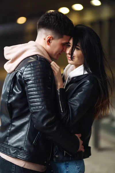 Young couple in love hug each other and have fun  in underground crossing. Couple of man and woman walking into a tunnel. Happy to be together. Love, romantic, passion, tenderness concept.