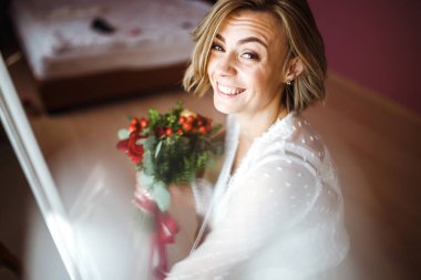 Çiçekli, beyaz, lüks elbiseli güzel gelin düğün için hazırlanıyor. Sabah hazırlıkları. Düğün makyajlı ve saç stili gelin. Düğün günü. Evlilik..