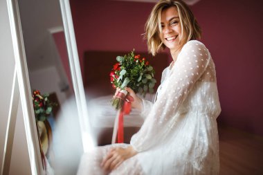 Çiçekli, beyaz, lüks elbiseli güzel gelin düğün için hazırlanıyor. Sabah hazırlıkları. Düğün makyajlı ve saç stili gelin. Düğün günü. Evlilik..