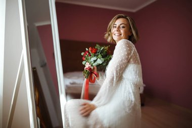 Çiçekli, beyaz, lüks elbiseli güzel gelin düğün için hazırlanıyor. Sabah hazırlıkları. Düğün makyajlı ve saç stili gelin. Düğün günü. Evlilik..