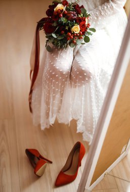 Düğün gününün detayları. Zarif beyaz elbiseli gelin gelinlerin elinde bir buket çiçek tutuyor. Güzel bir gelin tören için hazırlanıyor. Gelinin sabahı.