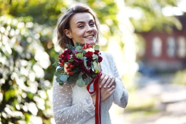 Parkta yürüyüş için bir buketi olan güzel bir gelin. Şık beyaz elbiseli genç gelin inanılmaz derecede mutlu. Profesyonel makyajlı ve saç stili olan zarif bir kadın. Düğün günü.. 