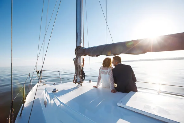 Beautiful wedding couple on yacht at wedding day outdoors in the sea. Beautiful elegant  bride in a white dress and stylish groom on the luxury yacht sailing down the sea. Together. Wedding day.