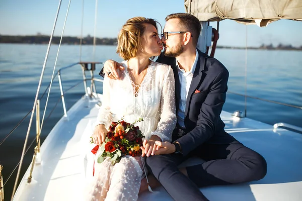 Beautiful wedding couple on yacht at wedding day outdoors in the sea. Beautiful elegant  bride in a white dress and stylish groom on the luxury yacht sailing down the sea. Together. Wedding day.