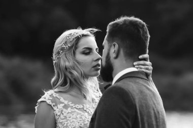 Siyah-beyaz, yeni evli çiftin düğün günü köprüde poz vermesini sağlıyor. Yakışıklı sakallı damat güzel gelini takdir eder ve öper. Birlikte. Gençlik, aşk, moda ve yaşam tarzı kavramı.