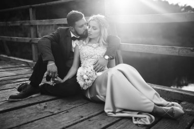 Siyah-beyaz, yeni evli çiftin düğün günü köprüde poz vermesini sağlıyor. Yakışıklı sakallı damat güzel gelini takdir eder ve öper. Birlikte. Gençlik, aşk, moda ve yaşam tarzı kavramı.