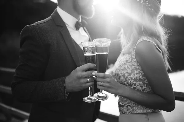 신부와 신랑의 샴페인을 부부들은 안경을 결혼식 다리에서 낭만적 순간을 즐긴다 — 스톡 사진