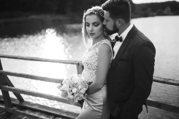 婚礼当天 一对新婚夫妇在桥上摆出一副黑白相间的狐狸造型 英俊的胡子新郎仰慕并亲吻漂亮的新娘 在一起 时尚和生活方式的概念 — 图库照片