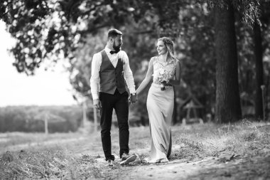 Gelin ve damadın şehvetli siyah beyaz foto 'su. Yeni evli çiftimiz düğün günlerinde parkta poz veriyormuş. Yakışıklı sakallı damat güzel gelini takdir eder ve öper. Birlikte.