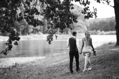 Gelin ve damadın şehvetli siyah beyaz foto 'su. Yeni evli çiftimiz düğün günlerinde parkta poz veriyormuş. Yakışıklı sakallı damat güzel gelini takdir eder ve öper. Birlikte.