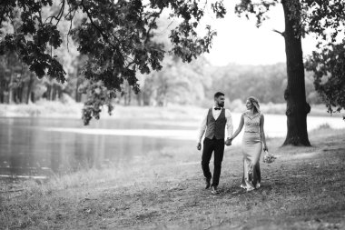 Gelin ve damadın şehvetli siyah beyaz foto 'su. Yeni evli çiftimiz düğün günlerinde parkta poz veriyormuş. Yakışıklı sakallı damat güzel gelini takdir eder ve öper. Birlikte.