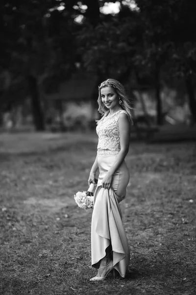 公園を散歩するための結婚式の花束と美しい花嫁の黒と白の写真 庭の緑の茂みの中に幸せな新婚女性が立っている 笑顔の花嫁 結婚式の日ファッション花嫁 — ストック写真