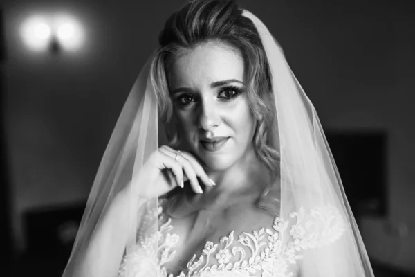 Black and white foto of beautiful bride with wedding flowers bouquet, attractive woman in wedding dress. Happy newlywed woman. Bride with wedding makeup and hairstyle. Morning of the bride.