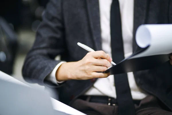 A man signs a contrac, legal or business agreements. Male hand with pen of young office worker makes notes. Business man  sitting at office desk and signing a document in modern office.
