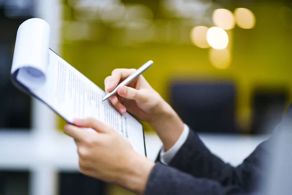 A man signs a contrac, legal or business agreements. Male hand with pen of young office worker makes notes. Business man  sitting at office desk and signing a document in modern office.