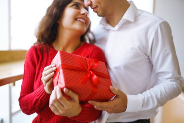 Mutlu çifti Noel hediyesi kucaklaşmalarıyla kapatın. Noel arifesinde birlikte eğlenen, hediyeli neşeli bir çift. Sevgililer birbirlerine hediyeler verir. Sevgililer Günü konsepti.