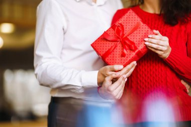 Elinde Noel hediyesi tutan bir adamla bir kadın. Noel arifesinde birlikte eğlenen, hediyeli neşeli bir çift. Kış tatili konsepti. Sevgililer birbirlerine hediyeler verir. Sevgililer Günü konsepti.