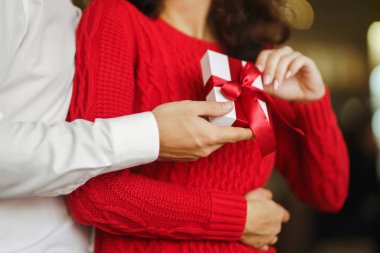 Sevgililer Günü, tatil ve sürpriz konsept. Adam karısına kırmızı kurdeleli bir hediye kutusu veriyor. Sevgi dolu bir çift restoranda sarılıp sevgililer gününü kutluyor. Sevgililer birbirlerine hediye verirler.